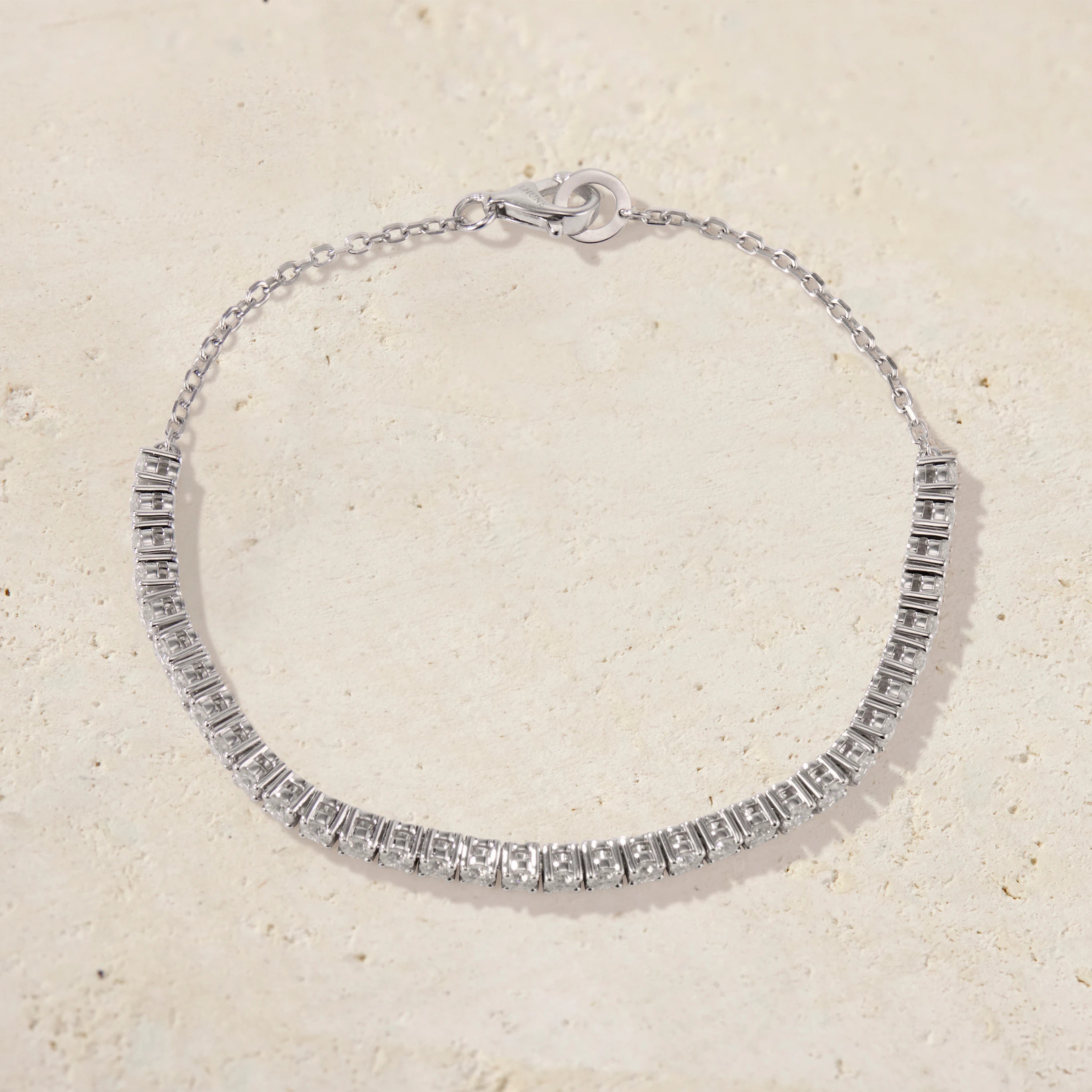 Silver bracelet with clear stones on a beige background