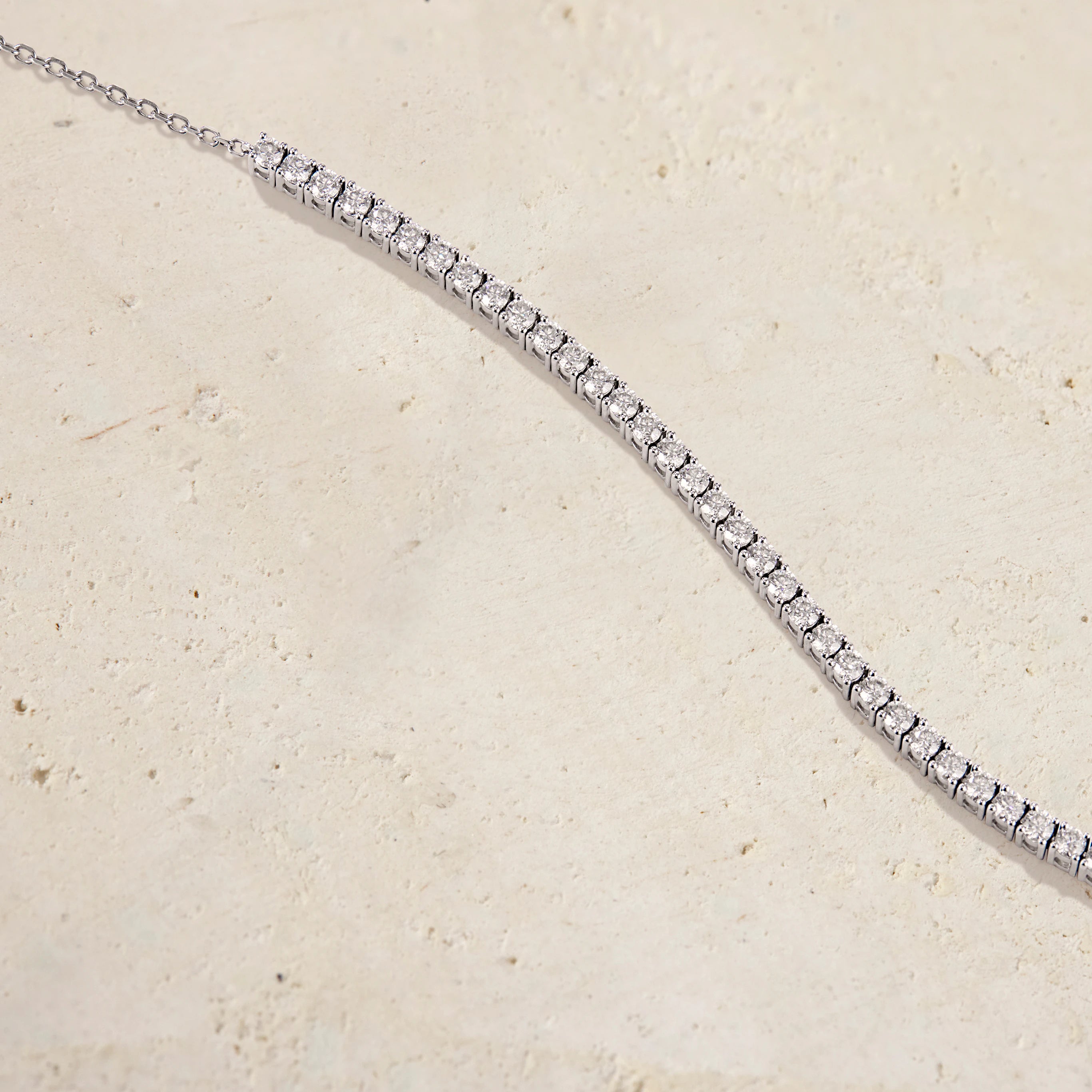 Silver bracelet with clear stones on a beige background