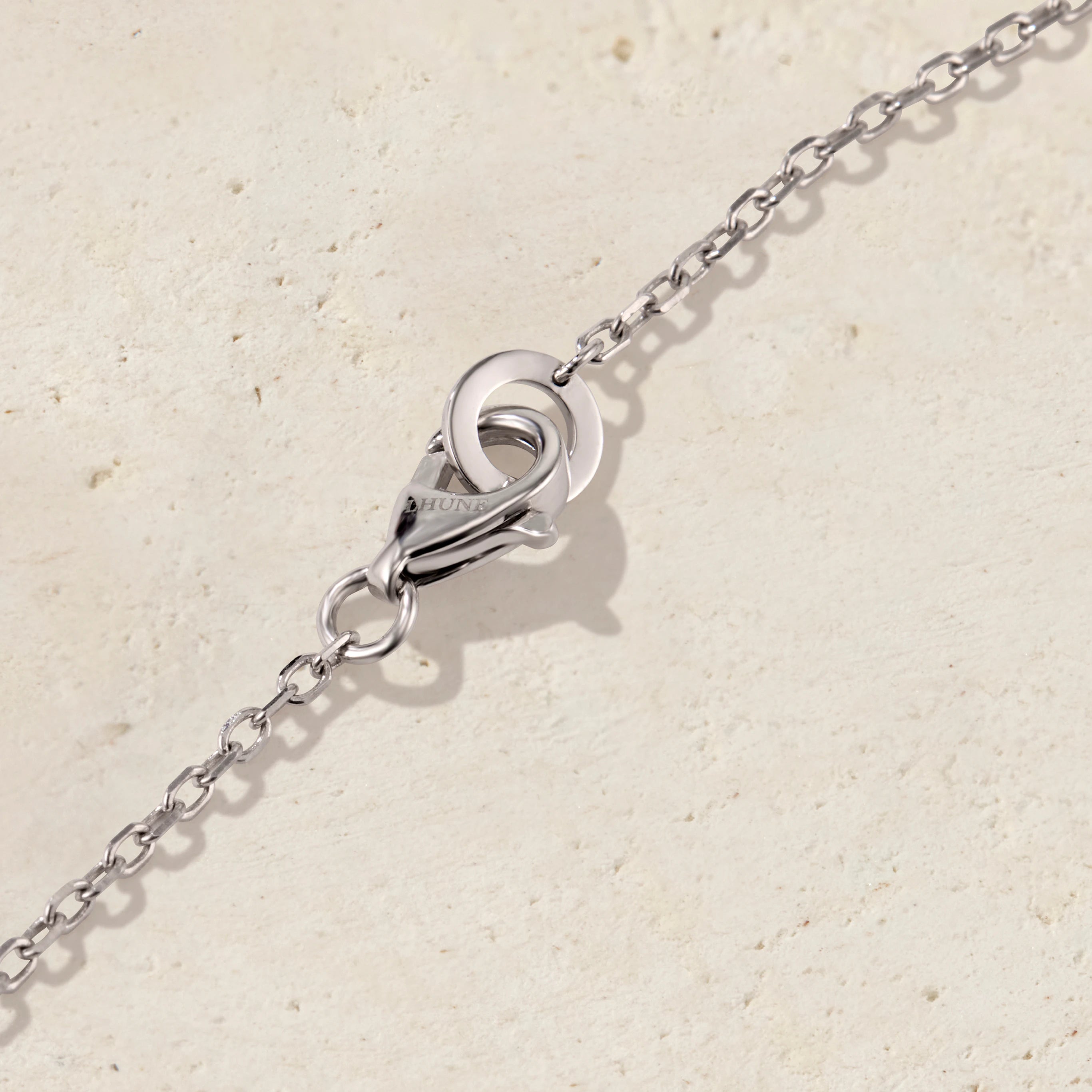 Close-up of a silver chain with a clasp on a beige background