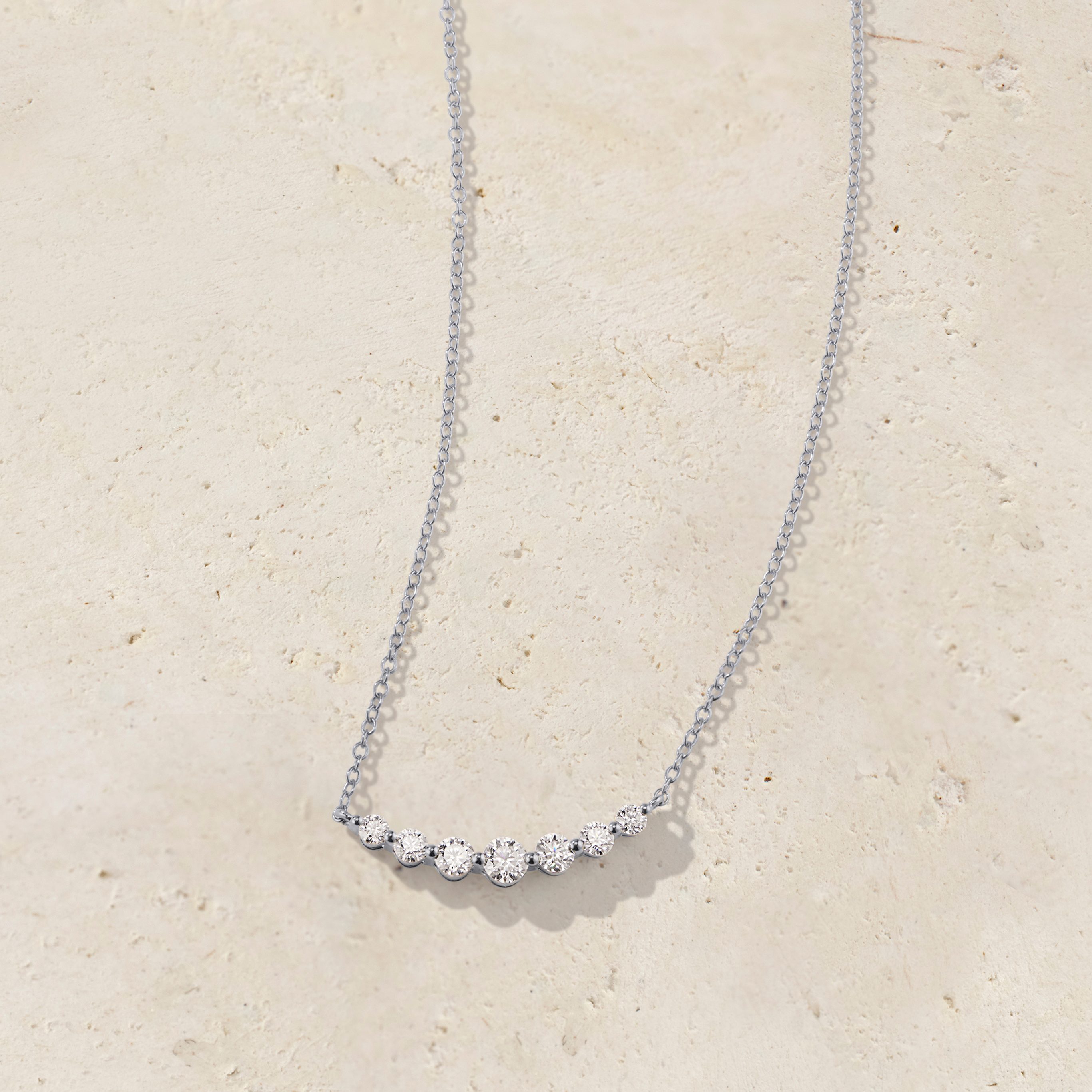LHUNE 7 Diamond Graduated Necklace, angled side view of seven graduating round diamonds on delicate cable chain