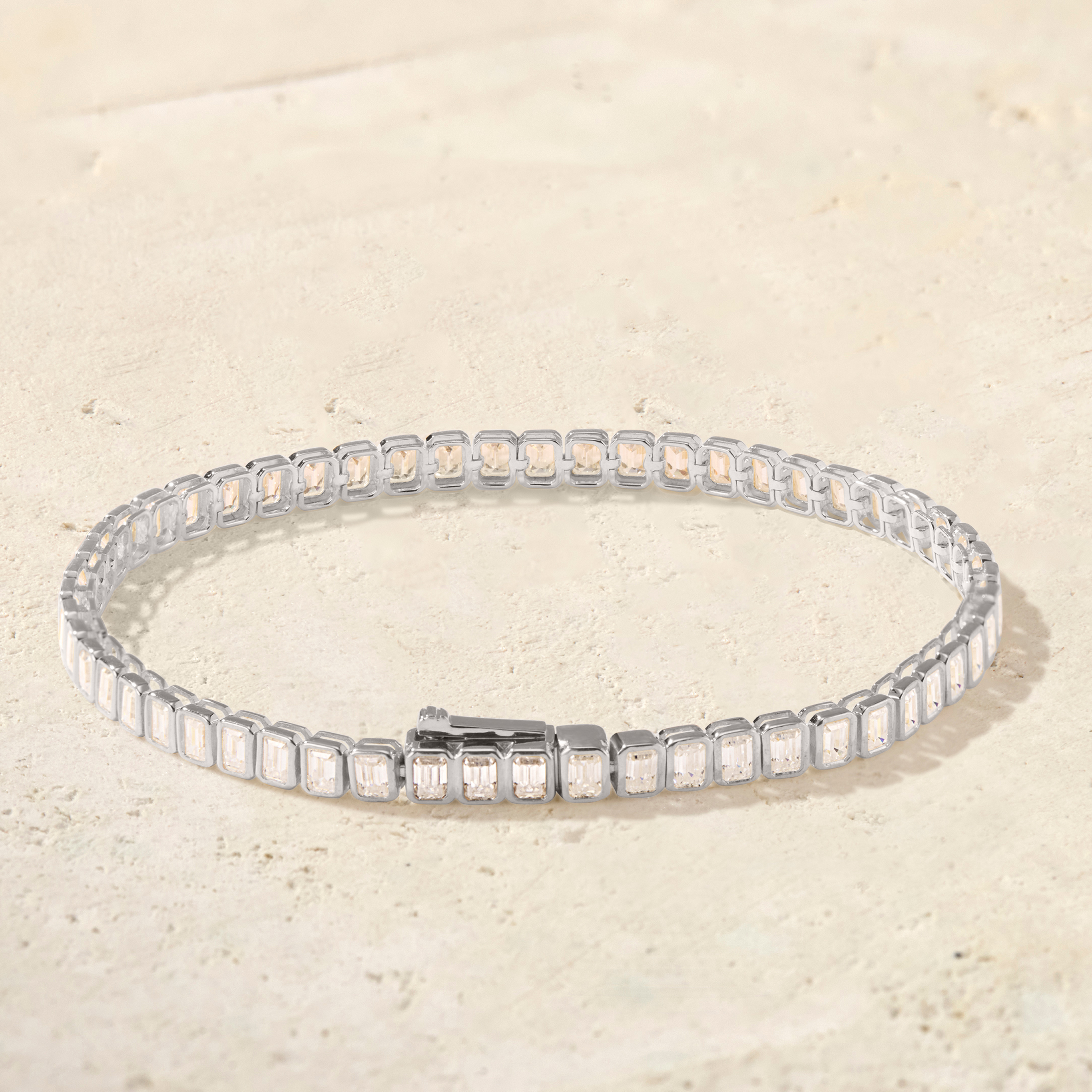 Silver bracelet with square-cut crystals on a beige background