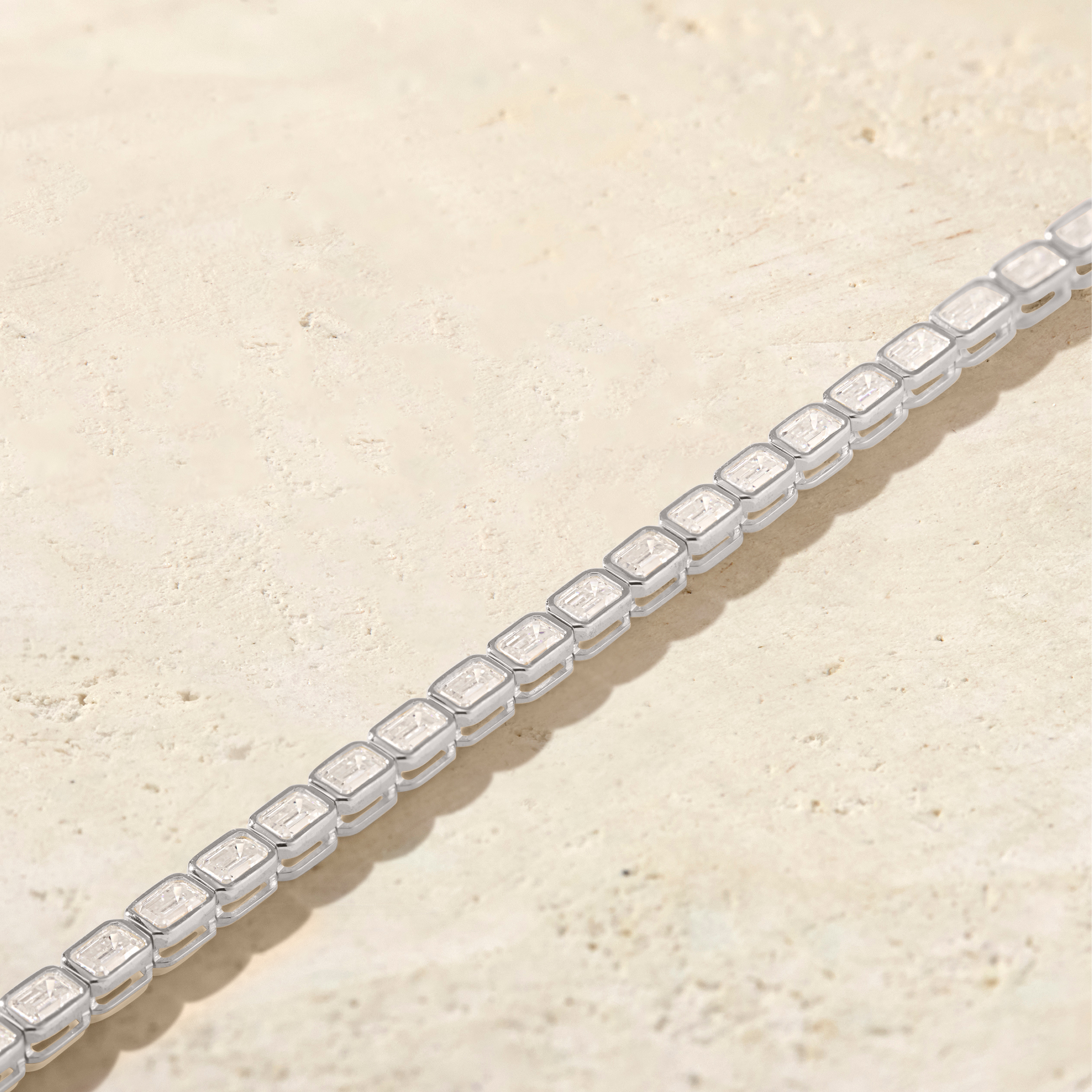 Silver bracelet with clear gemstones on a beige surface