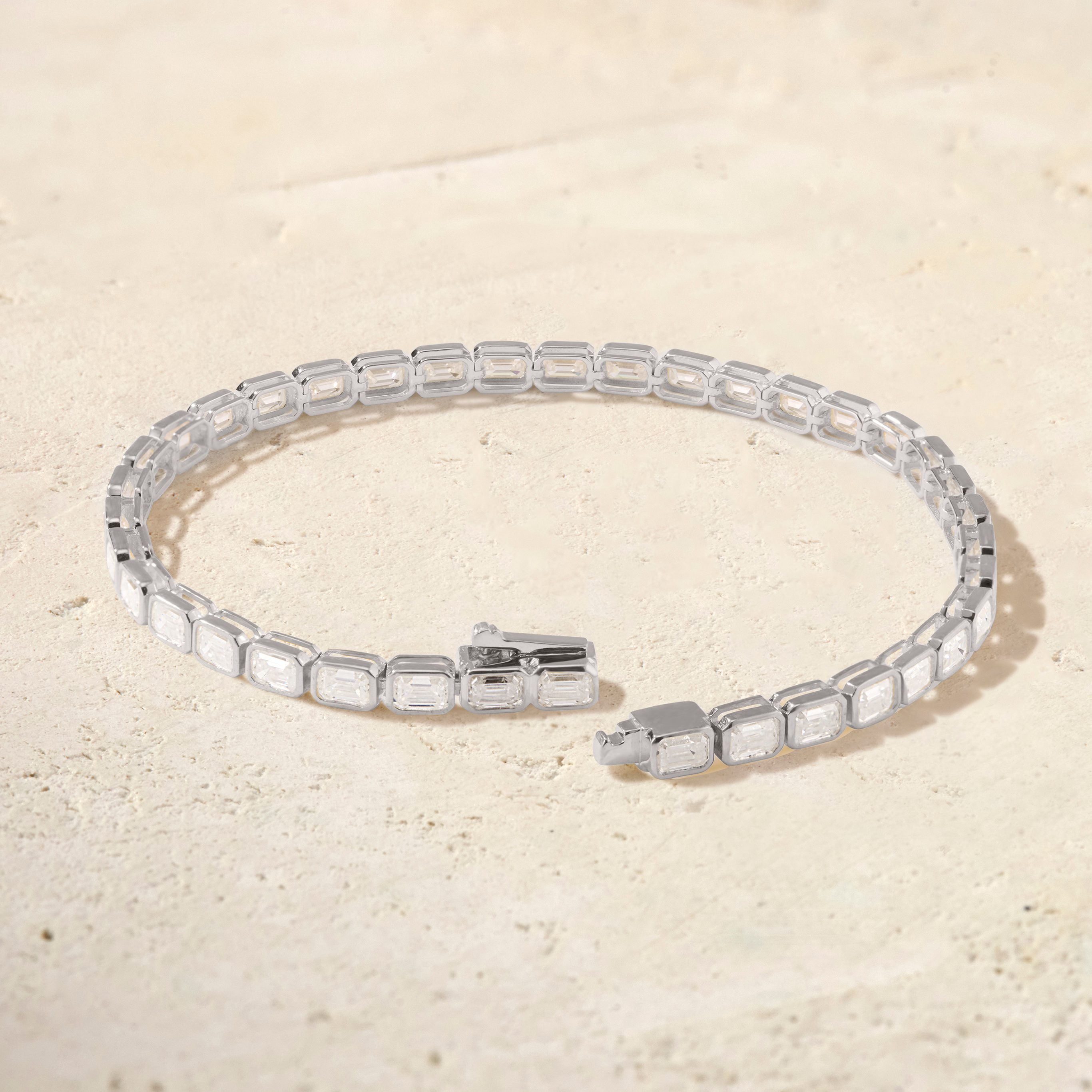 Silver bracelet with clear gemstones on a beige background
