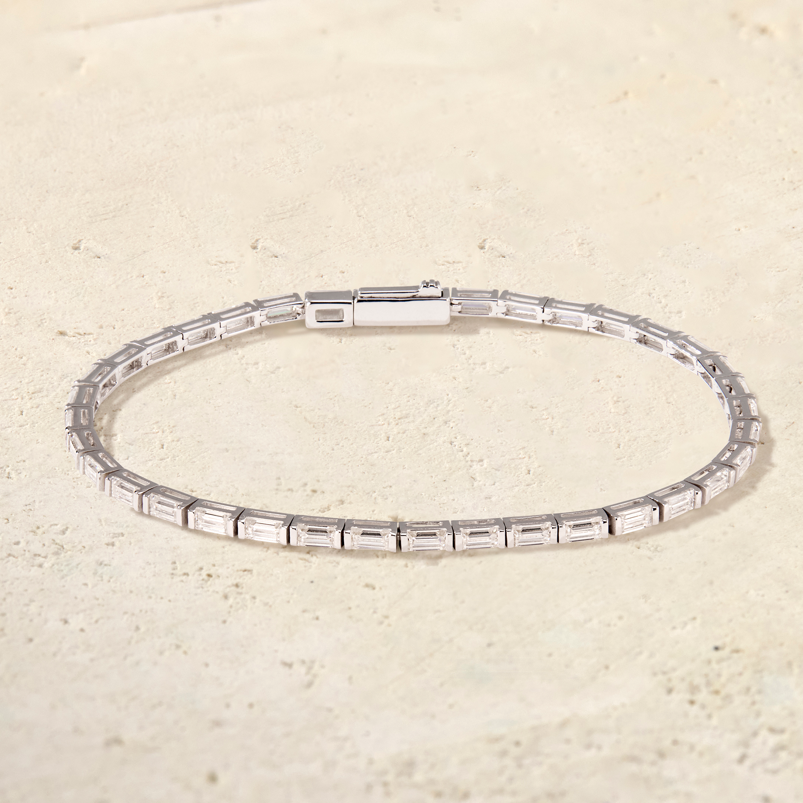 Silver bracelet with rectangular gemstones on a beige background