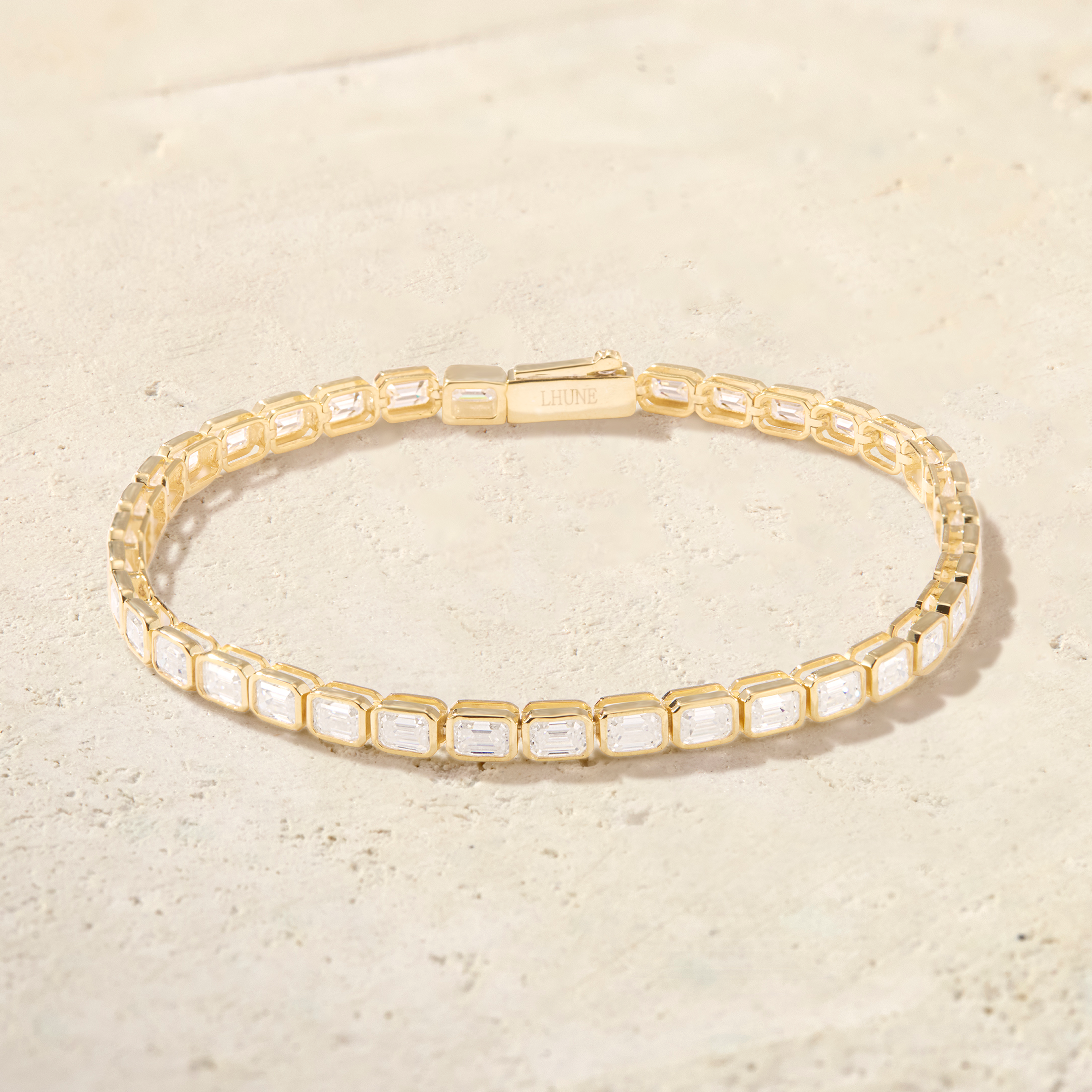 Gold bracelet with clear stones on a beige background