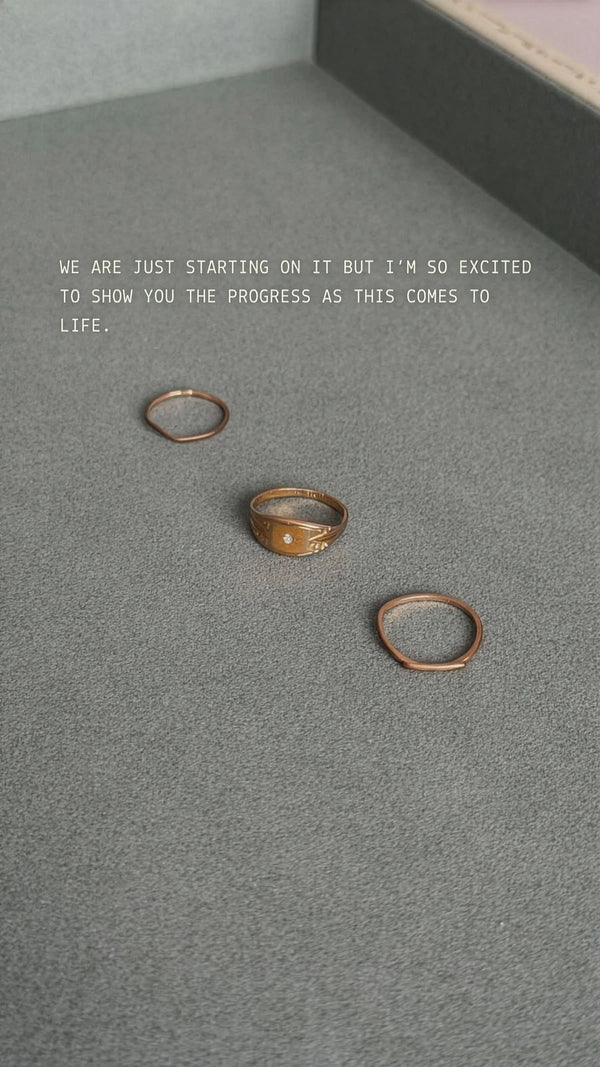 Three gold rings on a gray surface with a quote about progress.