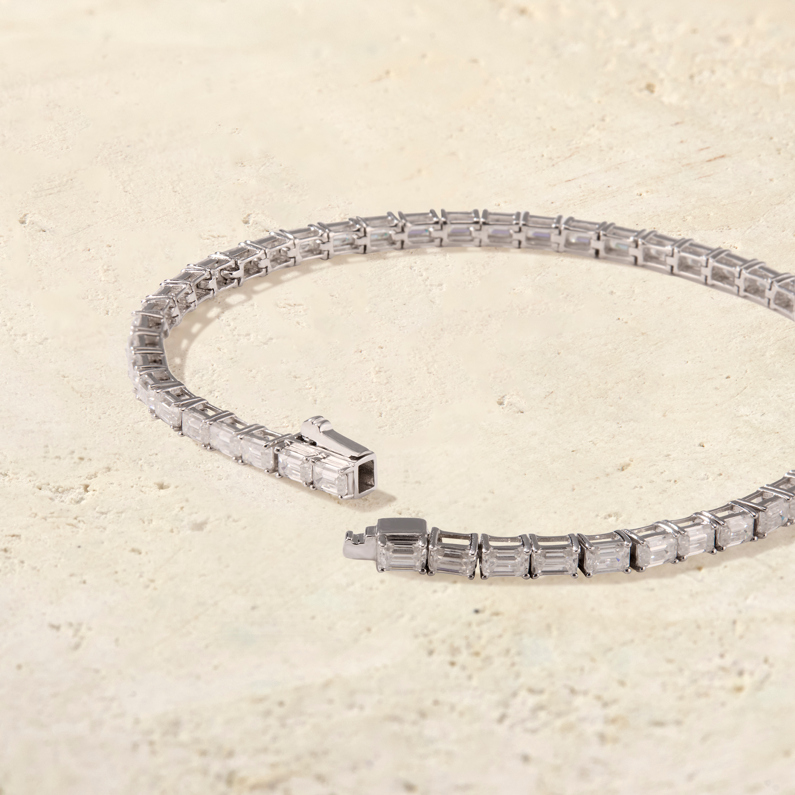 LHUNE Amara East-West Emerald-Cut Tennis Bracelet in white gold, open clasp detail on warm stone surface