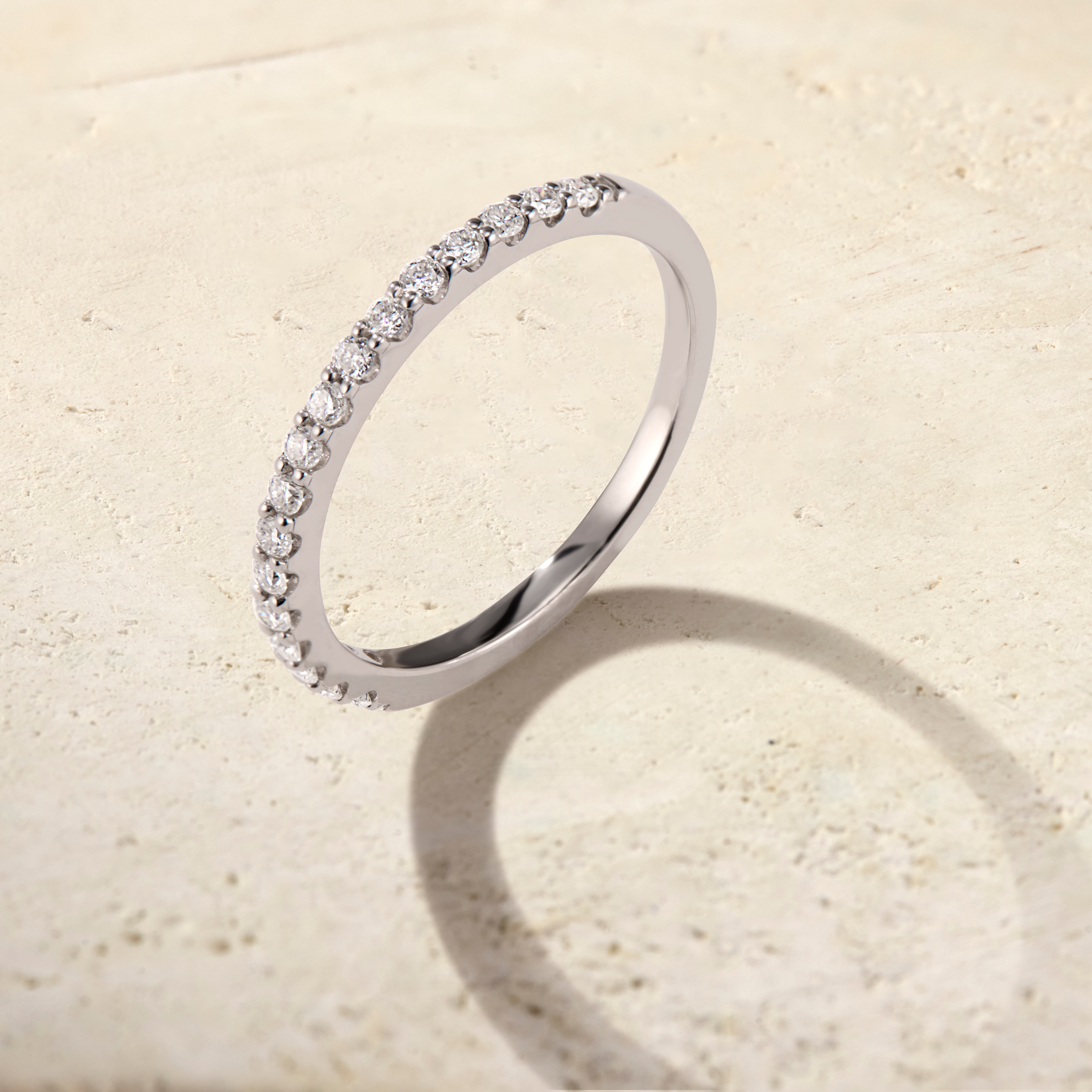 LHUNE Ciel Pavé Eternity Ring in white gold, left-angle view of pavé half-eternity band on warm stone surface