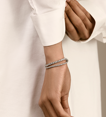 Hand wearing a silver bracelet on a plain background