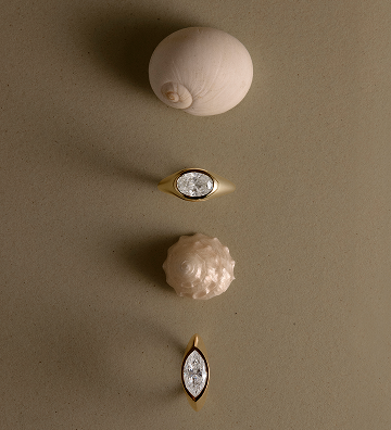 Two diamond rings on a beige surface with a neutral background